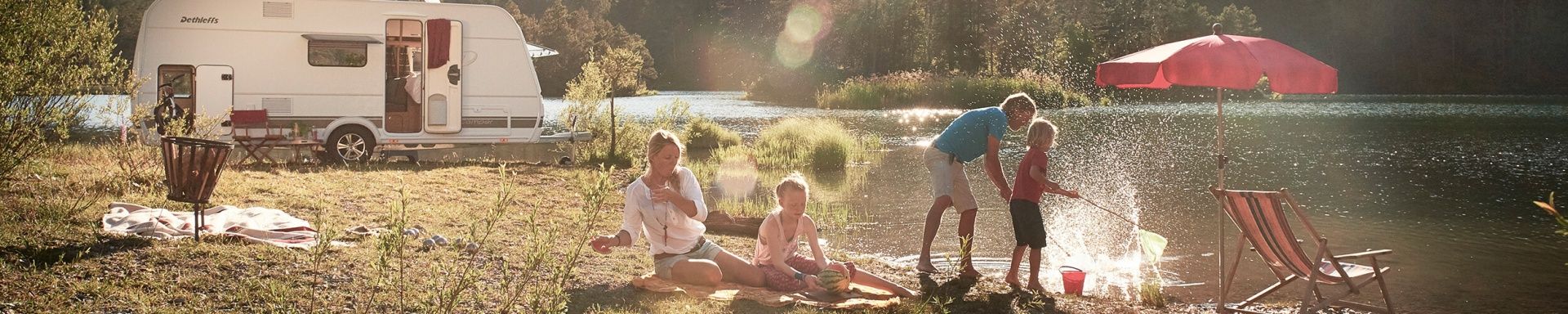 Die Eltern spielen mit ihren Kindern am Fluss, während des Campingurlaubs.